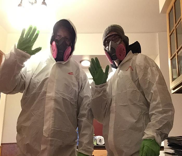 Two crew members in PPE waving their hands. 